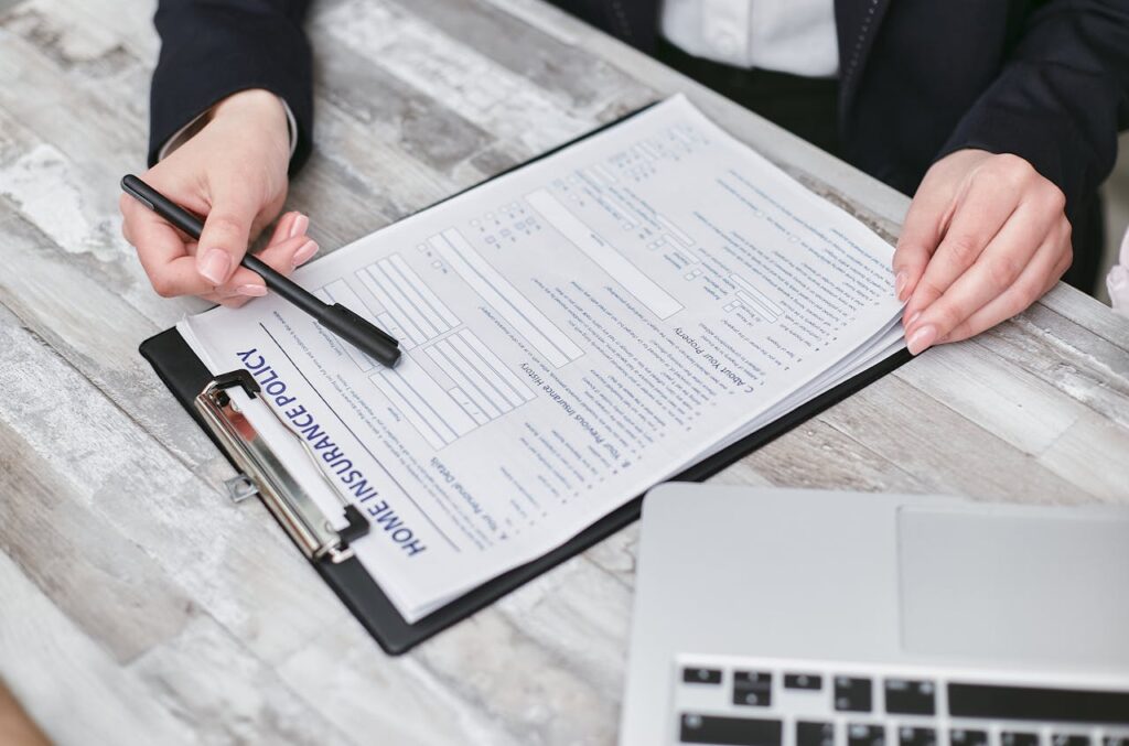Close-up of hands reviewing a home insurance policy, emphasizing professionalism and finance.
